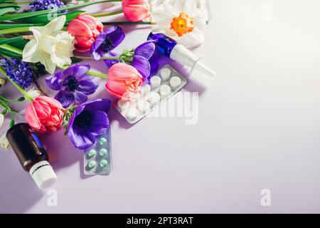 Allergia primaverile stagionale. Pillole e spray nasale piatto con fiori rosa viola bianco. Sanità e medicina. Vista dall'alto. Spazio Foto Stock