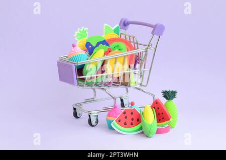 Carrello spesa è riempito al top con frutta fresca su uno sfondo viola. Il concetto di acquistare cibo e frutta online. Cucina dietetica Foto Stock