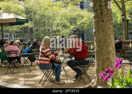 I visitatori possono godersi la soleggiata giornata primaverile a Bryant Park, un'oasi urbana nel centro di Manhattan, 2023, New York City, USA Foto Stock