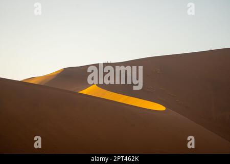 Turisti che scalano dune di sabbia, Sossusvlei, deserto del Namib, Namib-Naukluft Park, Namibia Foto Stock