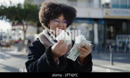 Giovane afroamericana sorridente fiduciosa contando i dollari per strada Foto Stock