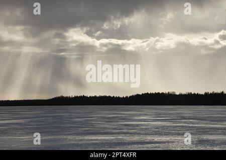 Paesaggio lacustre che piove all'orizzonte sul lago ghiacciato in Finlandia Foto Stock