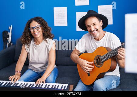 Musicisti uomo e donna che suonano pianoforte e chitarra classica in studio musicale Foto Stock