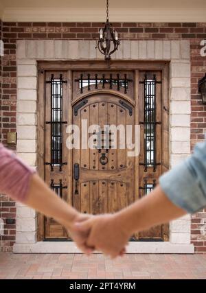 Coppia che tiene le mani che si avvicinano alla porta anteriore della casa. Foto Stock