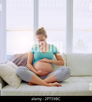 Legame con il suo fascio di gioia. una donna incinta che tiene il ventre a casa Foto Stock