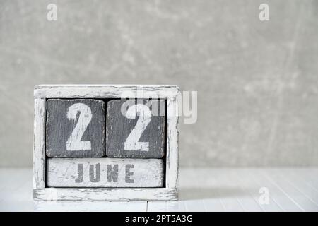 Calendario per giugno 22, fatto a cubetti di legno, contro parete di cemento chiaro.con uno spazio vuoto per il vostro testo Foto Stock