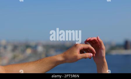 Le mani maschili e femminili si collegano in strada. Mani uomo e donna irriconoscibili che tengono in aria all'aperto. Primo piano di una coppia romantica di persone Foto Stock