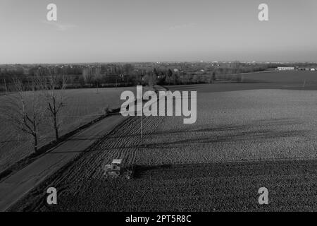 il contadino che guida un trattore cingolato trascina dietro una nuvola di polvere, arando, erpicando la rottura della crosta superficiale per facilitare la nascita e la semina di o Foto Stock