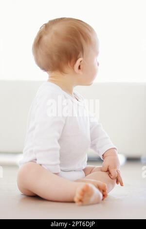 Dove andare adesso. un bambino piccolo che guarda intorno alla sua casa mentre si siede sul pavimento Foto Stock