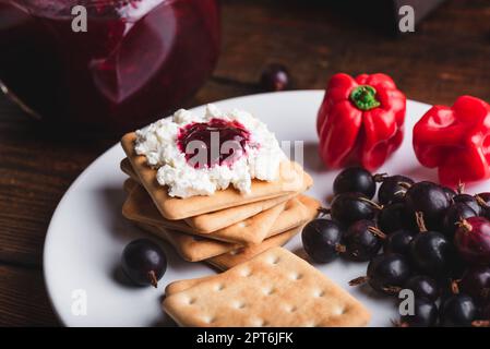 Confettura di uva spina e pepe rosso Habanero con formaggio cremoso sui cracker Foto Stock