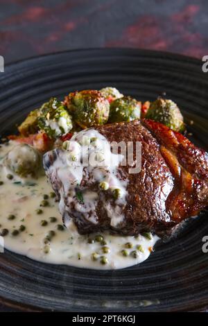 Bistecca di manzo fritto con cavolini di Bruxelles e cremosa salsa di piselli Foto Stock