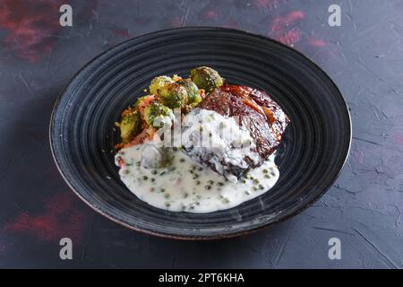 Bistecca di manzo fritto con cavolini di Bruxelles e cremosa salsa di piselli Foto Stock