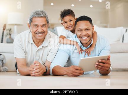 Trovare un buon equilibrio tra lavoro e amici e familiari. un uomo maturo che si posa con suo figlio e suo nipote sul pavimento mentre si utilizza un tablet a ho Foto Stock