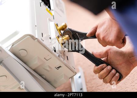 Strumenti e strumenti. Il riparatore maschio lavora con due chiavi regolabili contemporaneamente. Primo piano dei componenti di collegamento durante l'installazione del condizionatore d'aria. DIY c Foto Stock