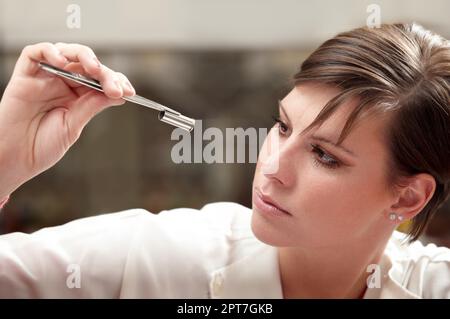 Esaminare ogni dettaglio. Un esperto di medicina legale che esamina un involucro della pallottola Foto Stock