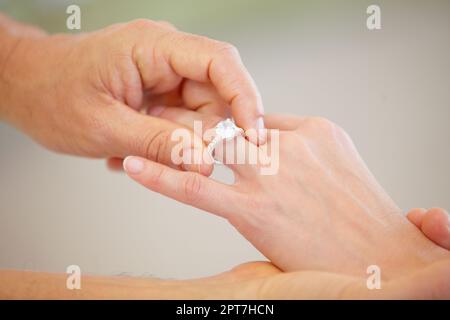 Un impegno che dura tutta la vita. Vista ritagliata di una mano mans che scorre un anello di nozze su un dito anello donna Foto Stock