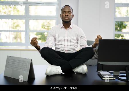 Dipendente africano che fa salute mentale meditazione Yoga in ufficio Foto Stock