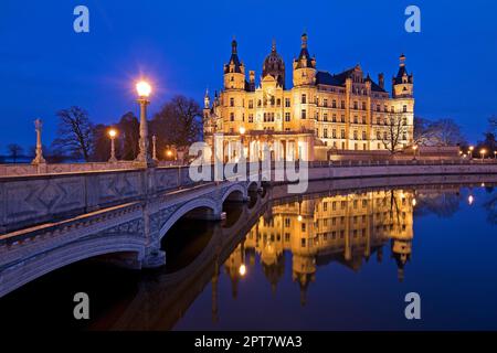 Castello di Schwerin illuminato con il ponte del castello per l'isola del castello in serata, Schwerin, Meclemburgo-Pomerania occidentale, Germania Foto Stock