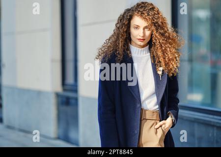 Giovane donna ambiziosa in lana camice camminare per strada Foto Stock