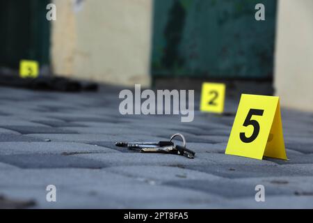 Prova con indicatore CSI giallo per la numerazione delle prove sul cortile interno in serata. Concetto del processo di indagine sulla scena del crimine Foto Stock