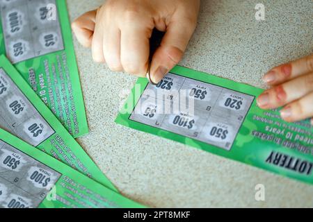 Vista ravvicinata della moneta d'argento in mano al giocatore che graffia la falsa carta della lotteria. Lotteria gioco d'azzardo concetto, gratta carte tipo di lotteria Foto Stock