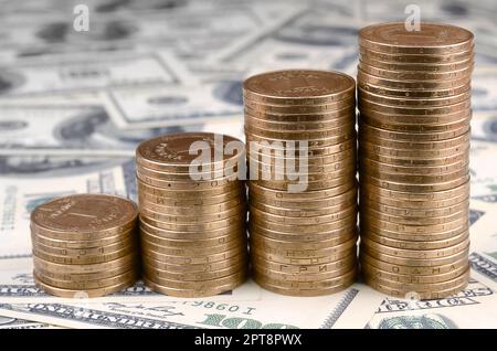 Pila di monete in Ucraina in un aumento delle pile di crescere. Denaro ucraino giace su di noi centinaia di fatture del dollaro Foto Stock