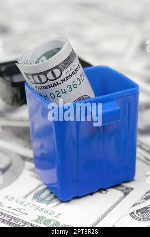 American cash note vengono gettati nel cestino della spazzatura su una moltitudine di centinaia di fatture del dollaro. Abbondanza finanziaria e l'eccesso di offerta. Insensata e spericolate c Foto Stock