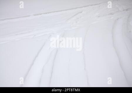 Tracce delle ruote della vettura su una strada innevata. Sterzata pericolosa e scivolosa del veicolo Foto Stock