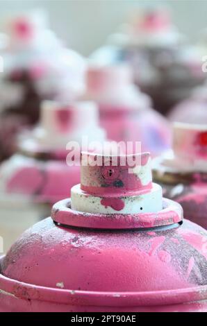 Un sacco di sporco e utilizzato le bombolette ad aerosol di rosa di vernice. Fotografia macro con profondità di campo ridotta. Messa a fuoco selettiva sull'ugello di spruzzo Foto Stock