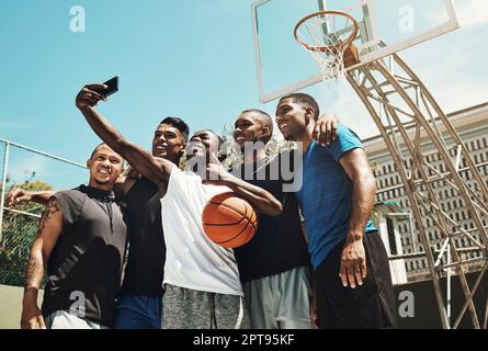 Selfie da basket, squadra di persone nere per il gioco, la concorrenza o i social media all'aperto dopo l'aggiornamento su blu cielo mock up. Influenzatore gruppo sportivo di uomini usi Foto Stock