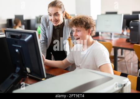 L'insegnante insieme agli studenti conduce una lezione sull'educazione informatica Foto Stock