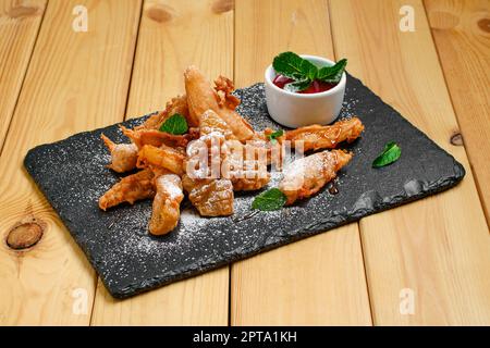 Frutta fritta profonda in panatura servita con caramello e confettura di fragole Foto Stock