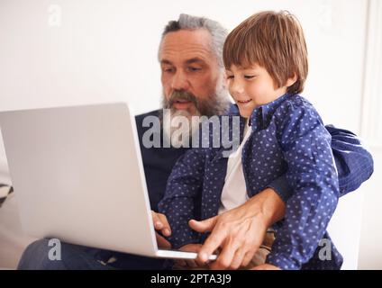 Aiutare nonno con il suo lavoro. Nonno e nipote che usano un notebook insieme Foto Stock