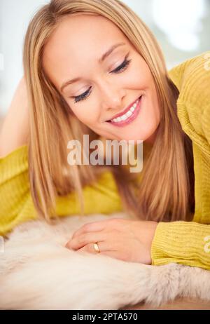 Il suo sorriso è una curva che ha messo tutto diritto. Una donna stesa comodamente sul pavimento della sua casa Foto Stock