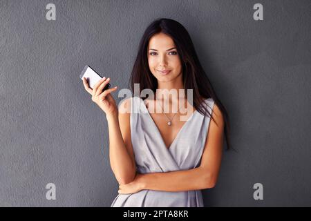 Voglio prendere il mio numero. Studio shot di una giovane donna attraente utilizzando il suo cellulare Foto Stock