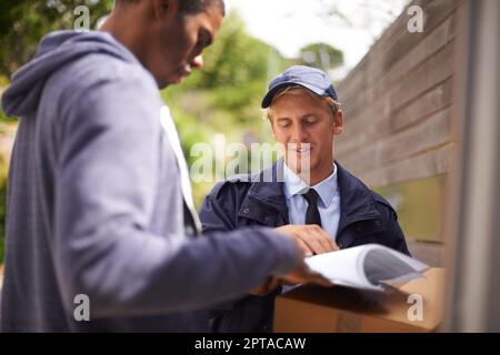 Inviare le sue cose sulla loro strada. un bel giovane firmando un modulo per un corriere Foto Stock