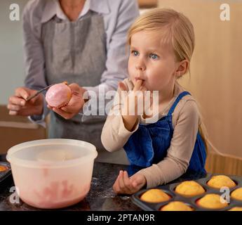 La ciliegina sulla torta è buona. una madre e le sue due figlie che cuocevano a casa Foto Stock