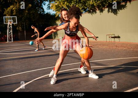 Shes buon a bloccarmi. un giovane sportivo attraente che blocca il suo avversario durante una partita di basket durante il giorno Foto Stock