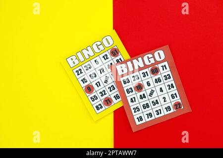Tavole di bingo gialle e rosse o carte da gioco per vincere chip. Carte Bingo classiche americane o canadesi da cinque a cinque su sfondo luminoso Foto Stock