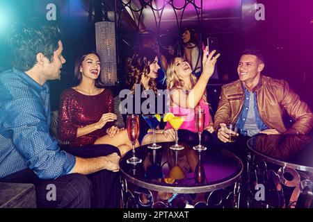 Circa ieri sera. un gruppo di amici che scattano selfie su un telefono cellulare in una discoteca. Foto Stock