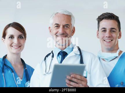 La tecnologia sta spianando la strada a nuove scoperte mediche. Tre medici professionisti che discutono le informazioni presentate su un tablet digitale Foto Stock