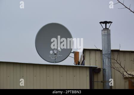 Realizzazione di una staffa per il montaggio di un'antenna parabolica sul tetto di un edificio Foto Stock