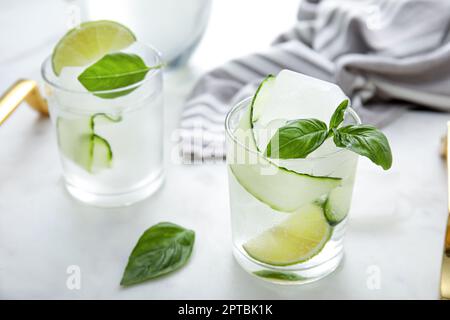 Gustosa acqua fresca di cetriolo con lime a fette e basilico su tavola bianca Foto Stock