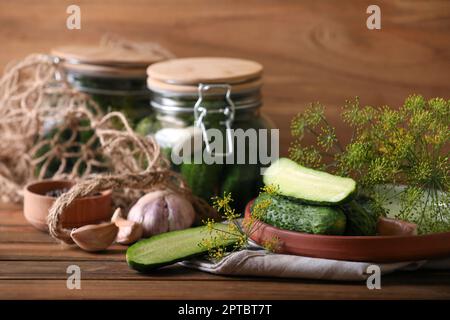Cetrioli freschi e altri ingredienti preparati per inscatolamento su tavola di legno Foto Stock