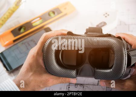 Progettazione architettonica di edifici tenere in sospeso gli occhiali VR 3D e i piani di costruzione con progetti cartacei, progettando man edit building o archi Foto Stock