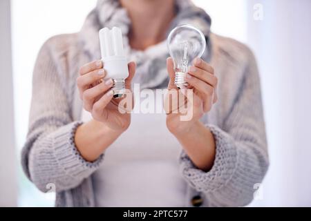 Momento della lampadina. Immagine ritagliata di una donna che tiene due lampadine diverse Foto Stock