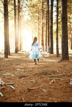 L'infanzia è un periodo magico. Foto vista posteriore di una bambina che cammina nel bosco con il suo orsacchiotto Foto Stock
