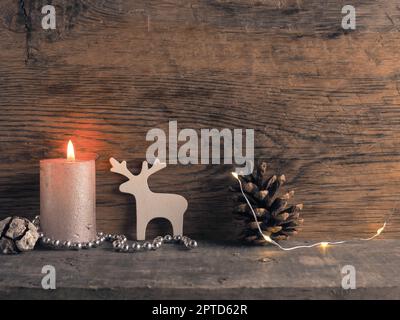 Candela del primo Avvento bruciature, coni di pino e decorazione di Natale su legno con luci di Natale Foto Stock