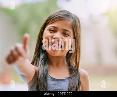 L'infanzia dovrebbe essere piena di grandi sorrisi e giorni felici. Ritratto di una bambina che mostra i pollici fuori Foto Stock