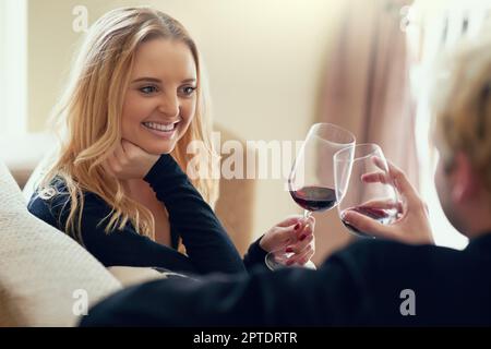 Eroe alla nostra vita piena di amore eterno. una giovane coppia gustando un bicchiere di vino insieme a casa Foto Stock